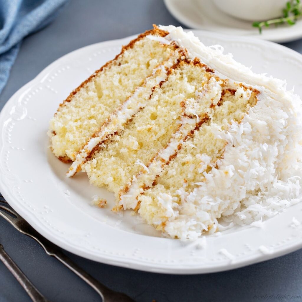 Moist homemade coconut cake with cream cheese frosting and toasted coconut flakes