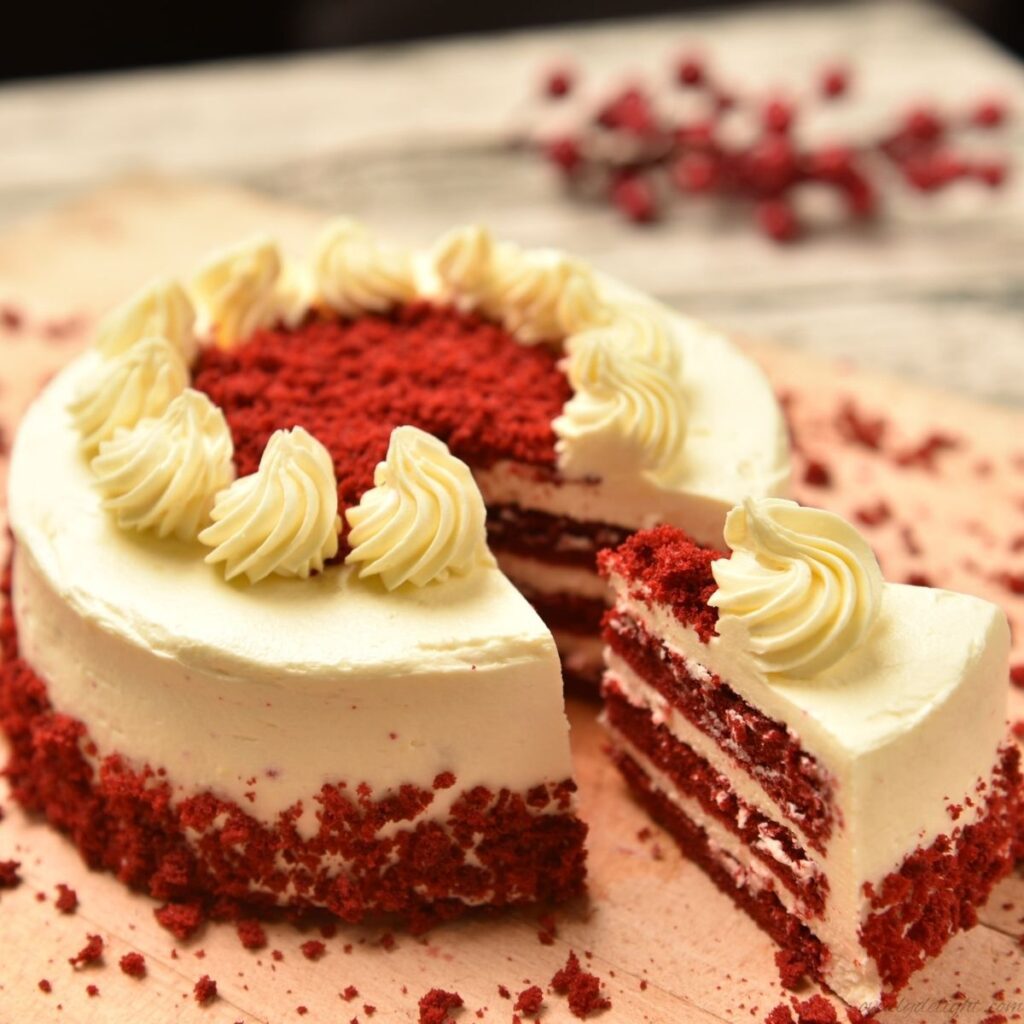 Red velvet layer cake with cream cheese frosting, soft red sponge, and smooth white icing.