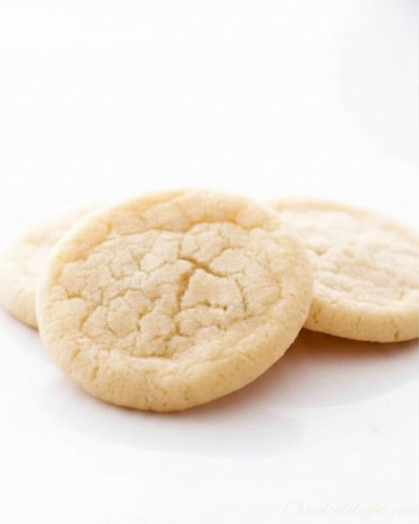 Soft sugar cookies stacked on a plate with a chewy center and golden edges