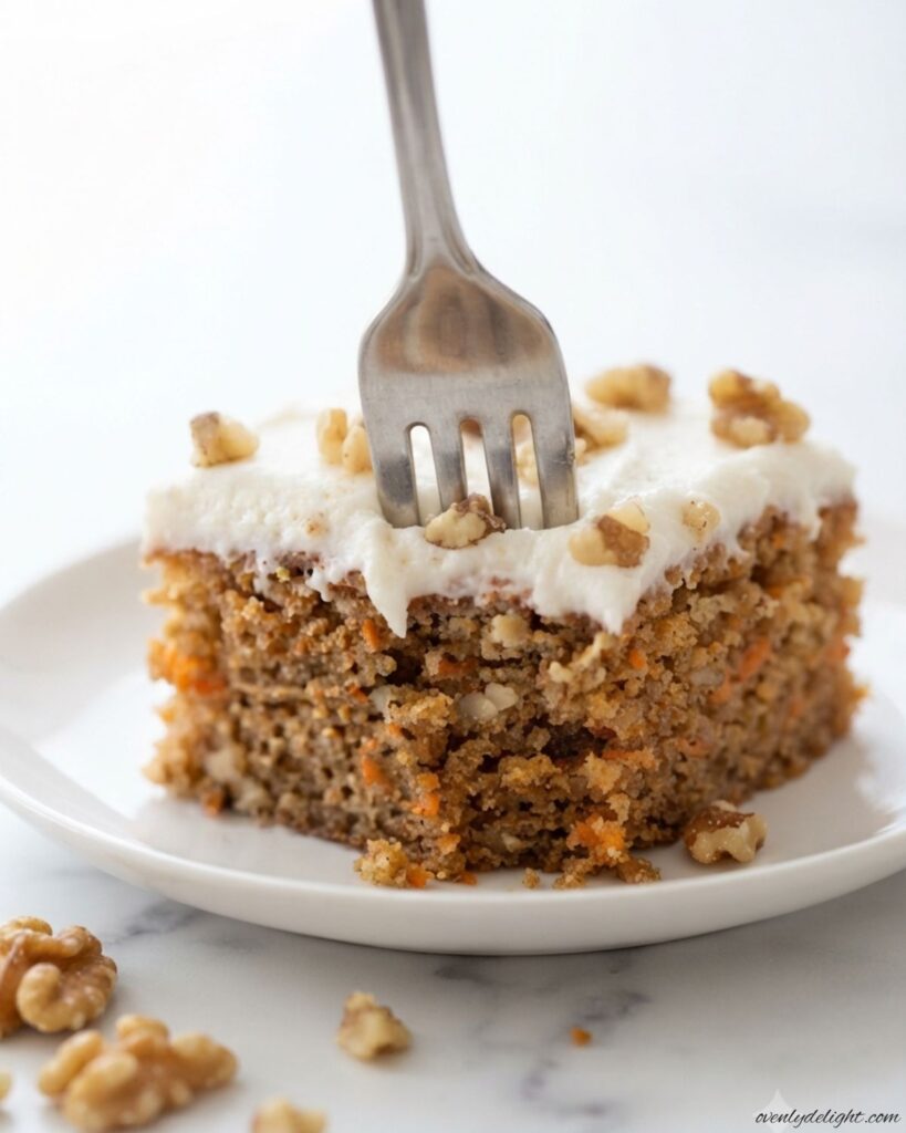 A freshly baked Moist Carrot Cake decorated with creamy frosting and crunchy walnuts for an easy homemade dessert.