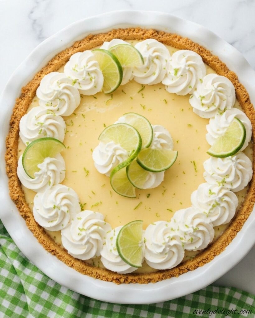 Creamy no bake key lime pie with a buttery graham cracker crust and fresh lime slices on top.