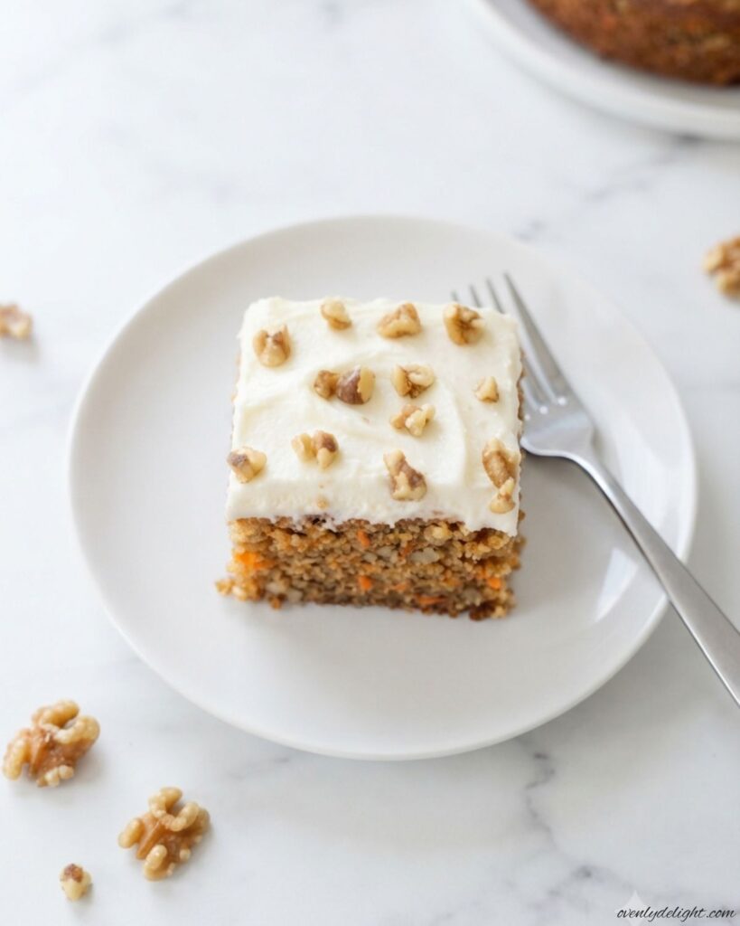 Thick slice of Moist Carrot Cake with a tender crumb, grated carrots, and tangy cream cheese frosting.