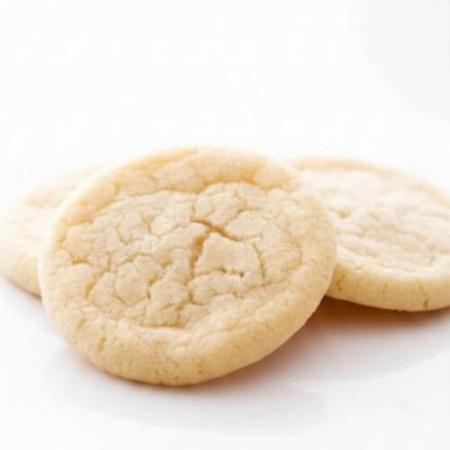 Soft sugar cookies stacked on a plate with a chewy center and golden edges