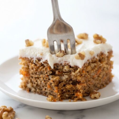 A freshly baked Moist Carrot Cake decorated with creamy frosting and crunchy walnuts for an easy homemade dessert.