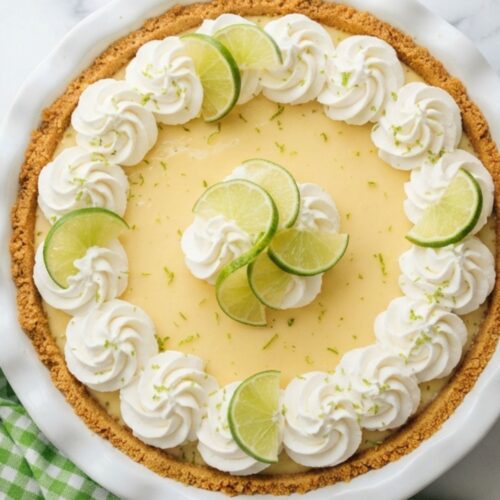 Creamy no bake key lime pie with a buttery graham cracker crust and fresh lime slices on top.