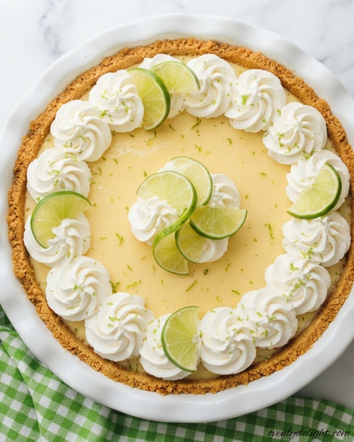Creamy no bake key lime pie with a buttery graham cracker crust and fresh lime slices on top.