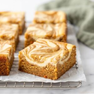 Homemade Carrot Cake Cheesecake Bars with a spiced carrot cake base and creamy cheesecake filling cut into neat squares.