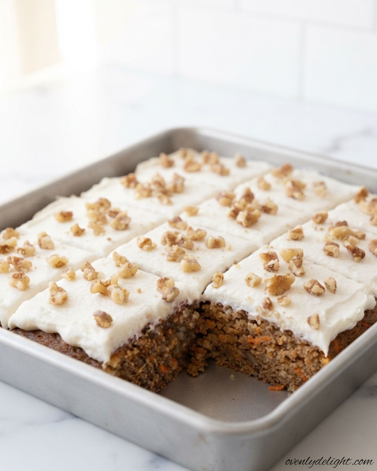 Moist Carrot Cake with rich cream cheese frosting and chopped walnuts, sliced and ready to serve.