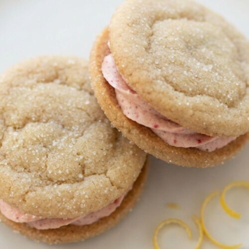 Easy lemon sandwich cookies featuring tangy lemon flavor and smooth strawberry frosting between each cookie.