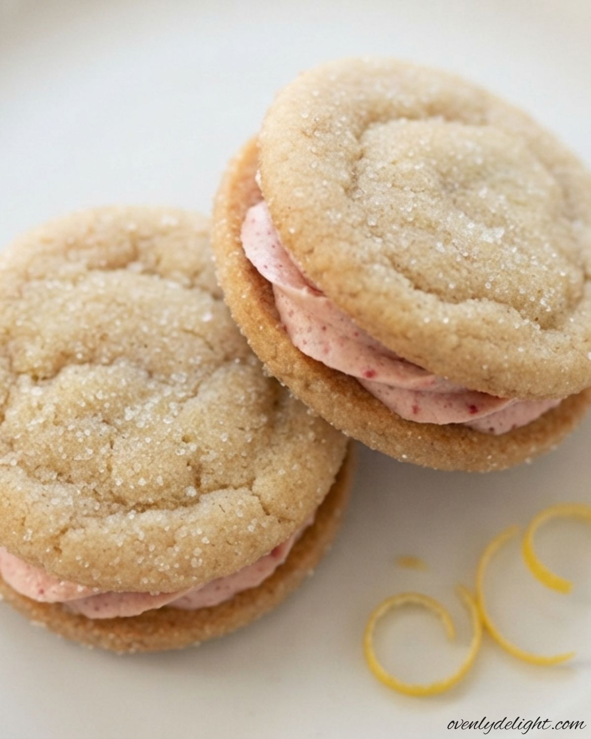 Easy lemon sandwich cookies featuring tangy lemon flavor and smooth strawberry frosting between each cookie.